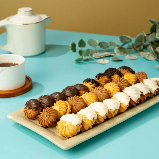 Assorted cookies on a plate with a cup of tea and teapot on a blue table. Petit Fours Box (Regular) Sale Sucre ساليه سوكريه
