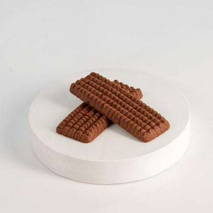 Three brown rectangular cookies on a white round platform with a white background  Biscuits ( Nashader - Chocolate - Orange )-Tseppas تسيباس