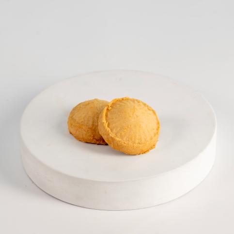 Two round, golden-brown pastries on a white plate with a white background Kahk - Tseppas