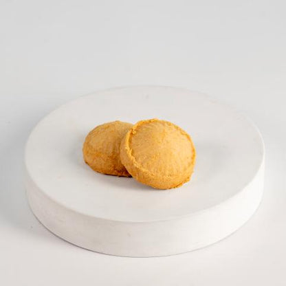 Two round, golden-brown pastries on a white plate with a white background Kahk - Tseppas